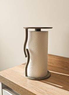 a roll of toilet paper sitting on top of a wooden counter next to a white wall