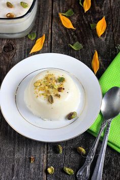 a white plate topped with dessert next to a green napkin and silverware on top of a wooden table