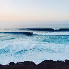 an ocean view with waves crashing on the rocks