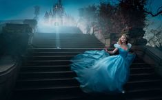 a woman in a blue dress is walking down some stairs