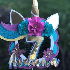 a cake topper with the number seven on it and flowers in front of it