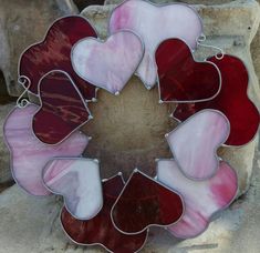 a red and white heart shaped stained glass piece on top of a pile of rocks