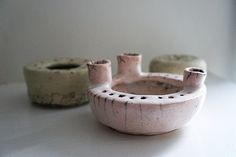 two clay pots sitting on top of a white table next to each other with holes in them