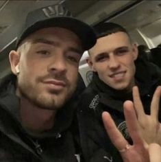 two young men posing for the camera with their hands in the air and one holding his hand up