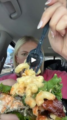 a woman eating food in the back seat of a car while holding onto a fork