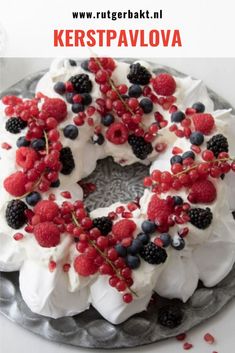 a cake decorated with berries and white frosting on a silver plate next to candles