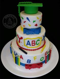 a three tiered cake decorated with letters, numbers and a mortar on it's side