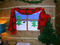 a christmas scene is displayed in the corner of a room with plaid curtains and trees