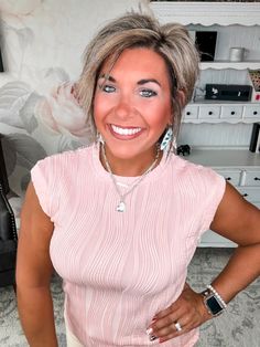 a woman with grey hair and blue eyes smiles at the camera while standing in her living room