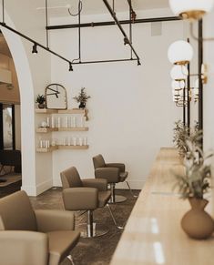 the interior of a hair salon with chairs and plants in vases on the counter