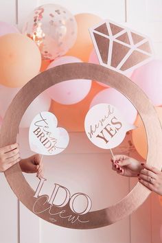 two people holding up some paper cutouts in the shape of a ring with words on it