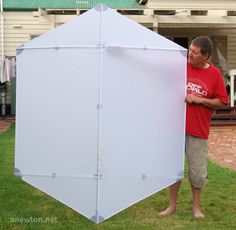 a man holding a large white object in front of his face while standing on the grass