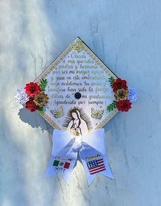 a decorated graduation cap hanging on the side of a white wall with red and blue flowers