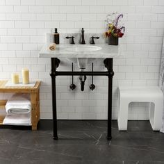 a white bathroom sink sitting next to a wooden shelf with candles and flowers on it