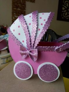 a pink and white baby carriage made out of paper with glitter on the rims