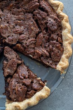 a chocolate pecan pie on a plate with a piece missing from it and text overlay