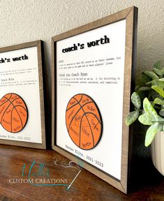 two framed basketballs are sitting on a wooden table next to a potted plant