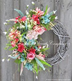 a wreath with flowers and greenery hanging on a fence