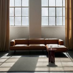 a brown leather couch sitting in front of two windows