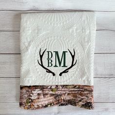 the monogrammed deer antlers are on this white quilt