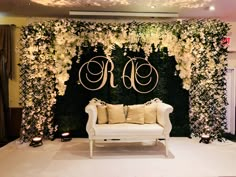 a white couch sitting in front of a flower covered wall with the initials on it