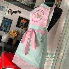 a pink and blue apron on display in a store window with other items behind it