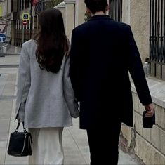 a man and woman walking down the street holding hands