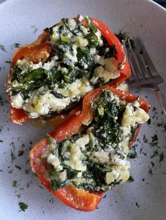 two stuffed bell peppers with spinach and cheese on top are sitting on a white plate