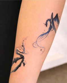 a woman's arm with a tattoo on it that has mountains and stars painted on it