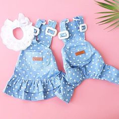 two pairs of blue and white polka dot overalls on pink background with palm leaf