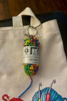 a white bag with a crochet keychain hanging from it's side