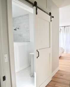 an open door leading to a bathroom with white walls and wood floors in the background