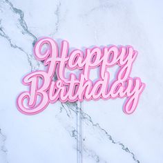 a pink happy birthday cake topper on a marble surface