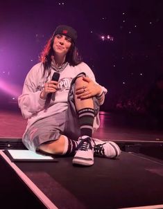 a woman sitting on top of a stage holding a microphone