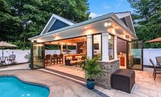 a backyard with a pool, patio and dining area next to the swimming pool is lit up at night