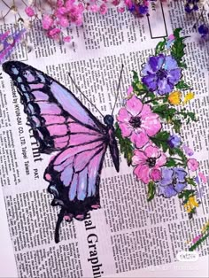 a butterfly sitting on top of a newspaper next to flowers