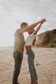 a man and woman dancing on the beach