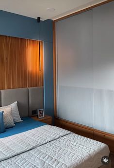 a bed sitting in a bedroom next to a window with blinds on the side of it