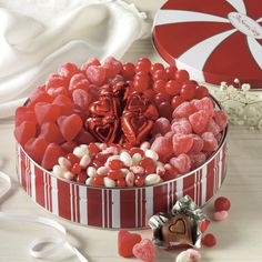 red and white candies in a heart shaped tin next to a box of candy