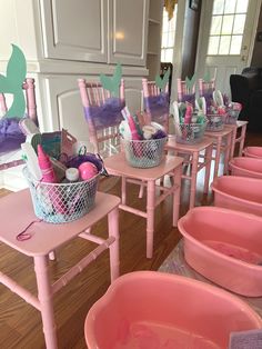 there are many pink tubs with toothbrushes in them on the tables and chairs