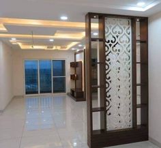 an empty room with white tile flooring and decorative screens on the walls, along with large windows