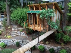 a small house built into the side of a hill surrounded by trees and rocks with a walkway leading up to it