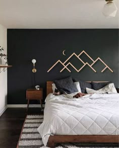 a bedroom with black walls, white bedding and wooden head board on the wall