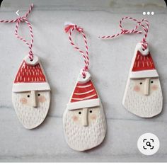 three ceramic santa claus ornaments hanging from red and white twine with string on each ornament