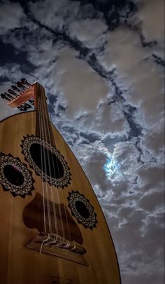 a large wooden guitar sitting under a cloudy sky