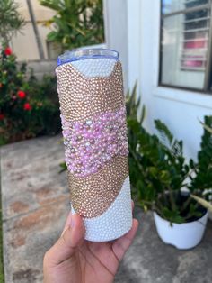 someone is holding up a cup decorated with pink and white beads on the outside of it