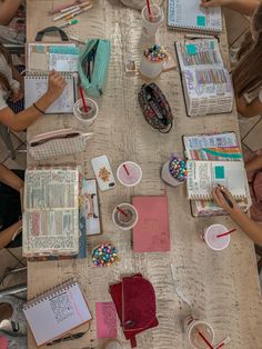 people are sitting at a table with books and notebooks on it, reading the bible