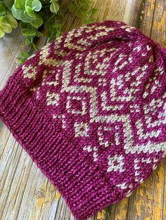 a knitted hat sitting on top of a wooden table next to a potted plant