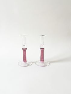 two pink glass candlesticks sitting next to each other