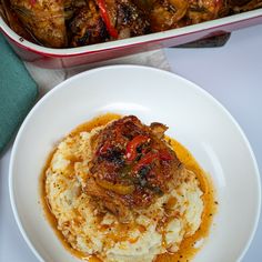 a white plate topped with mashed potatoes next to a casserole dish filled with meat